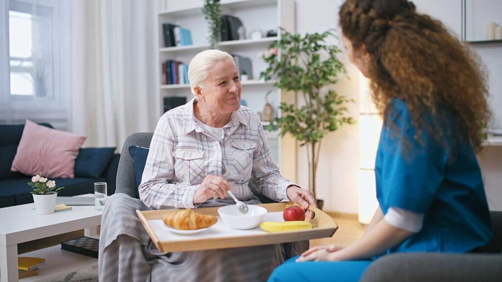Older adult arranging familiar belongings in a new assisted living room with family support.