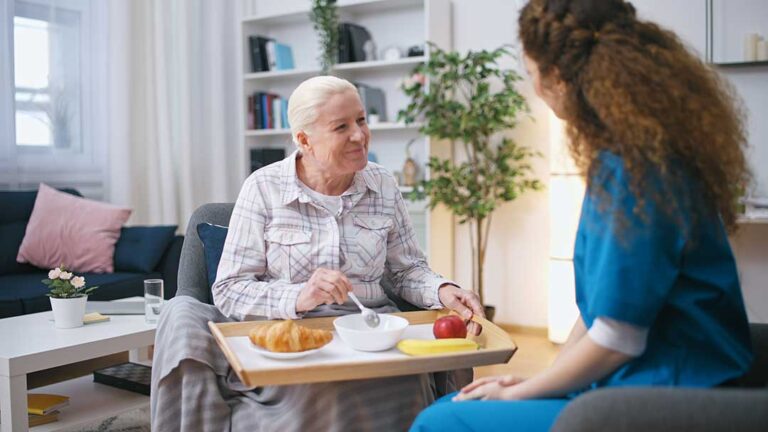 Older adult arranging familiar belongings in a new assisted living room with family support.